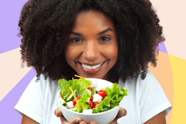 Mulher regra de cabelos Afro segurando um pote de salada